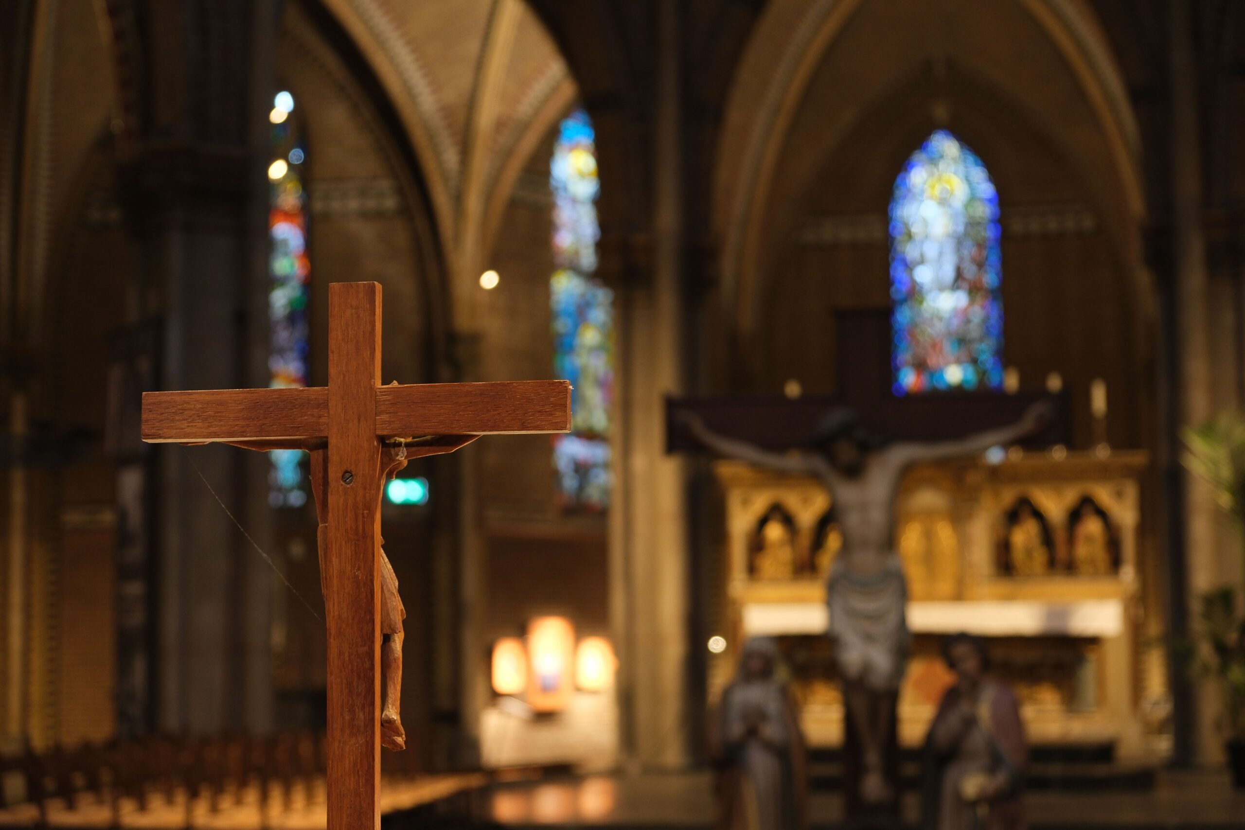 Church interior with a wooden crucifix, stained-glass windows and an altar.