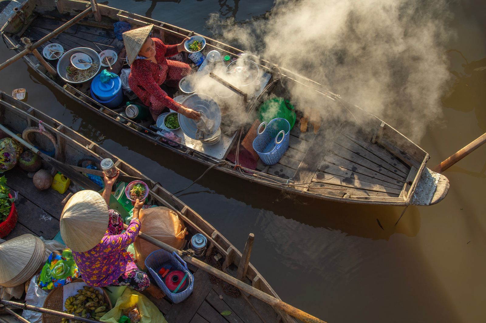 Vendors prepare food on boats at a Vietnamese floating market
