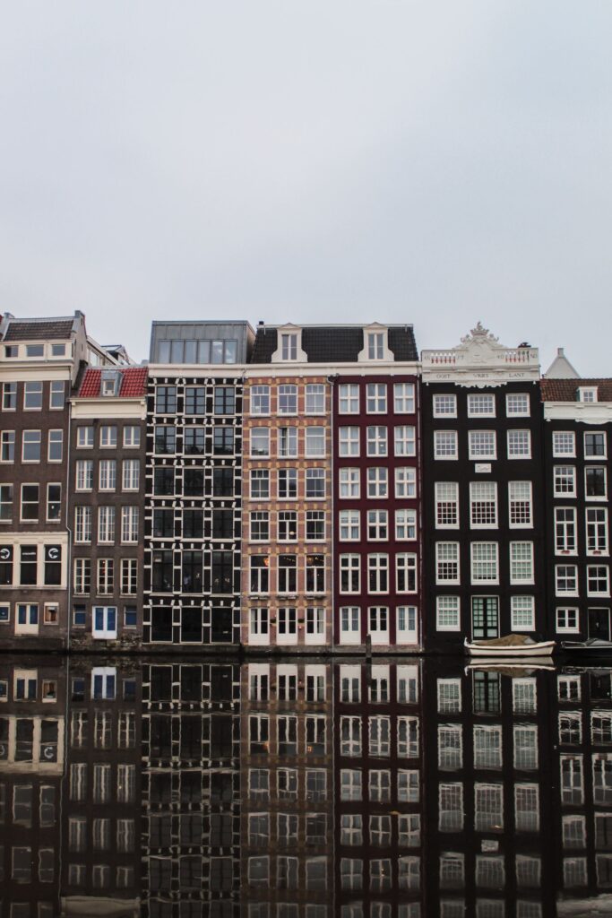 Narrow Amsterdam canal houses and their reflections across the water.
