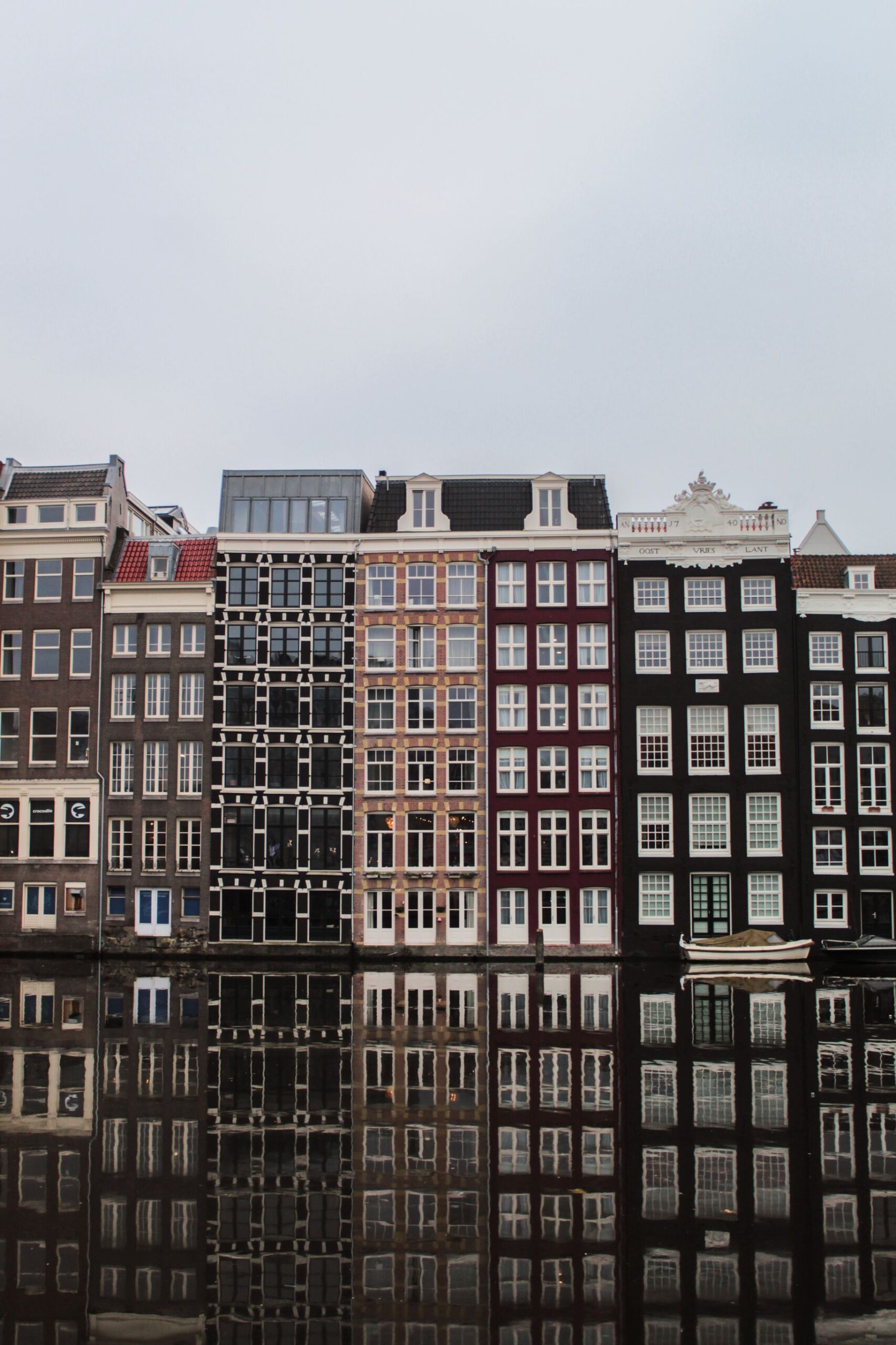 Narrow Amsterdam canal houses and their reflections across the water.