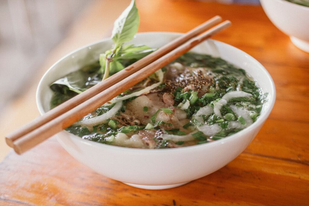 Bowl of Vietnamese noodle soup with fresh herbs and sliced meat