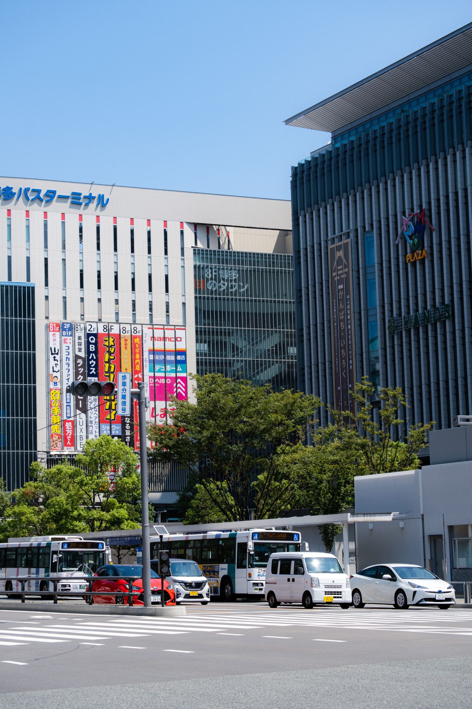 Buses and street lights outside the Hakata station-area buildings