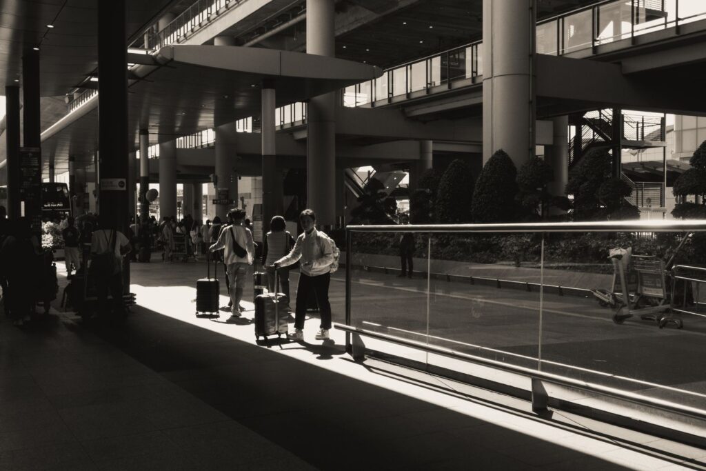 Travelers with suitcases walking through a sunlit airport terminal