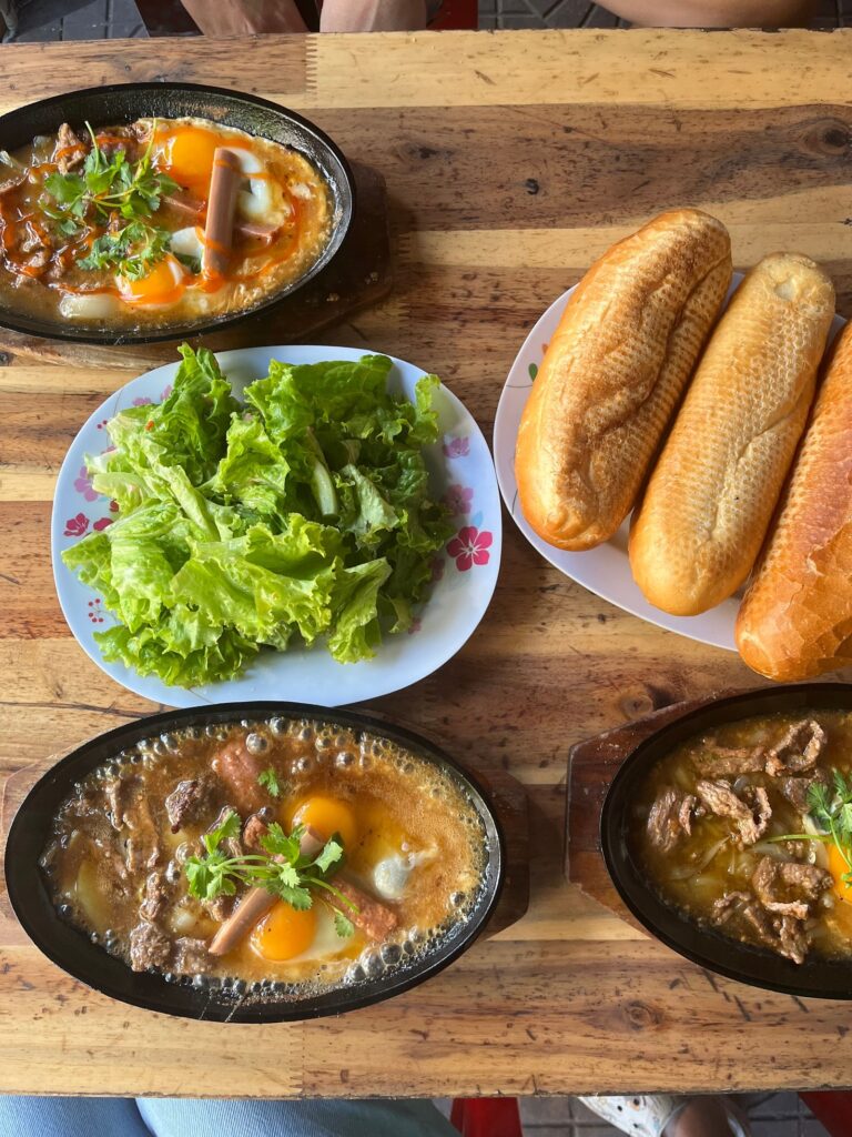 Vietnamese sizzling breakfast with eggs, meat, herbs, and baguettes