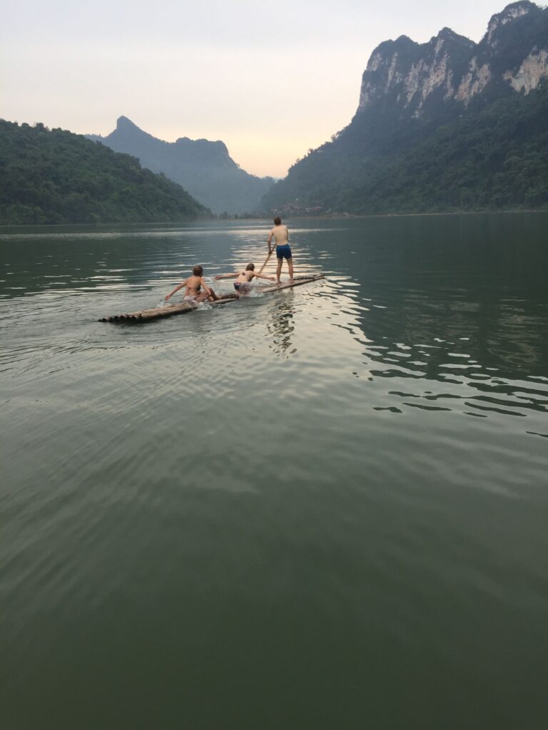 Visitors ride a narrow bamboo raft across a mountain lake in Ba Be