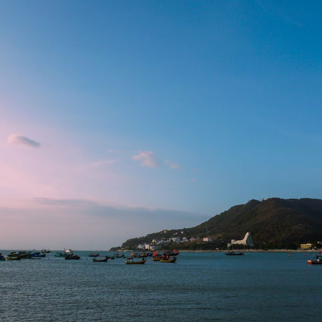 Fishing boats on a coastal bay with green hills and buildings in Vung Tau