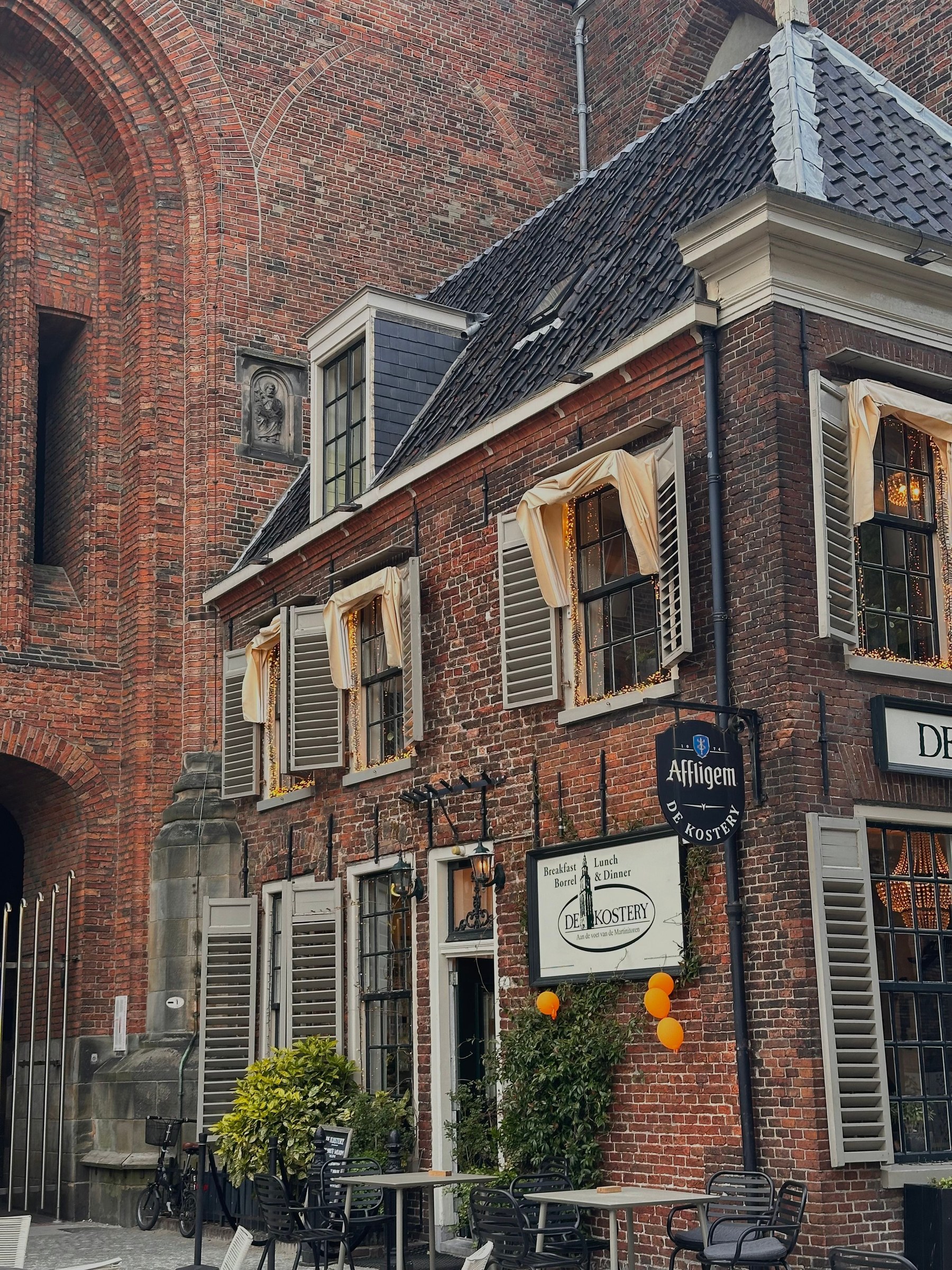 A red-brick facade with outdoor cafe tables in Groningen’s old town.