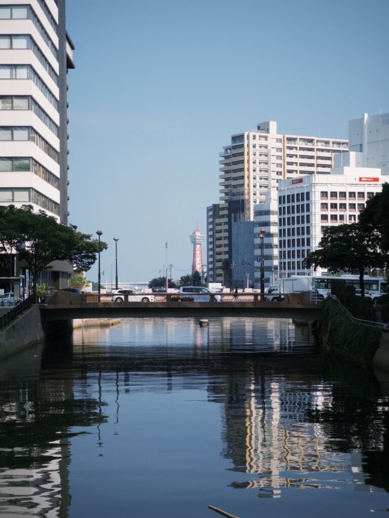 Riverfront buildings and a bridge reflected in water in Fukuoka