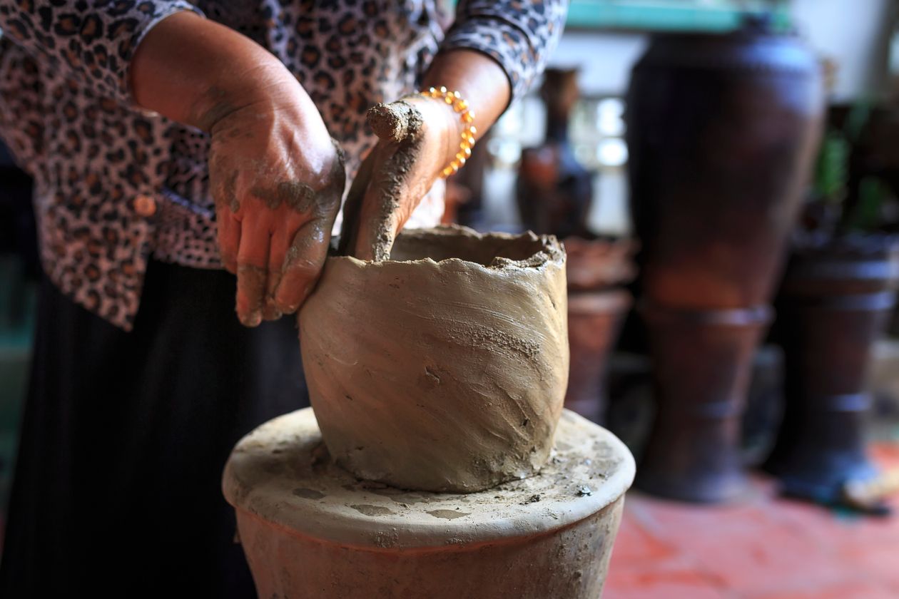 Potter shaping a wet clay vessel by hand
