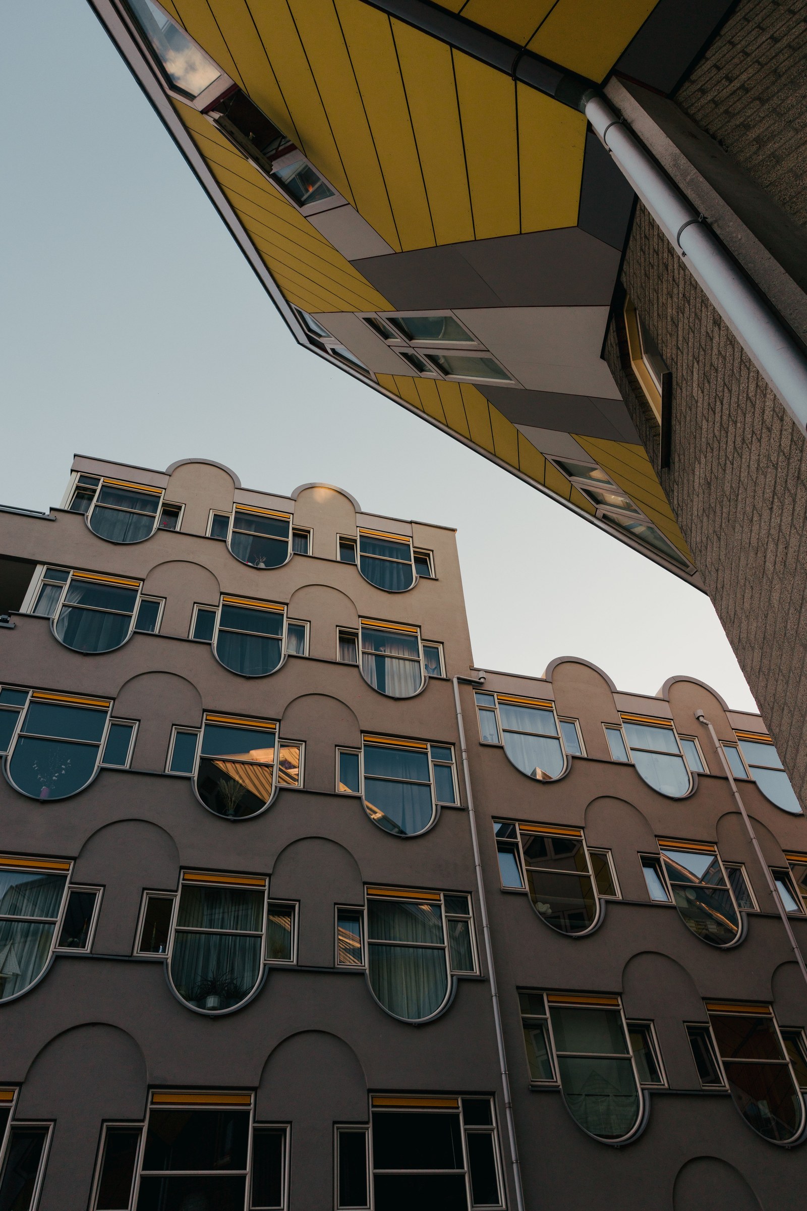 Looking upward at angular yellow and gray building facades in Rotterdam.