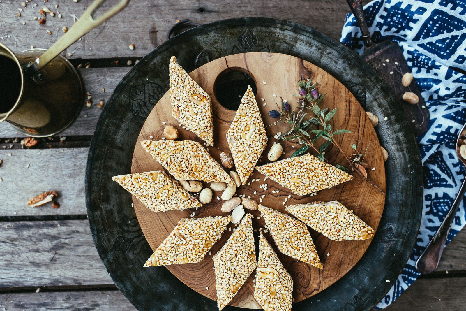 Diamond-shaped sesame candy pieces with visible peanuts on a wooden board