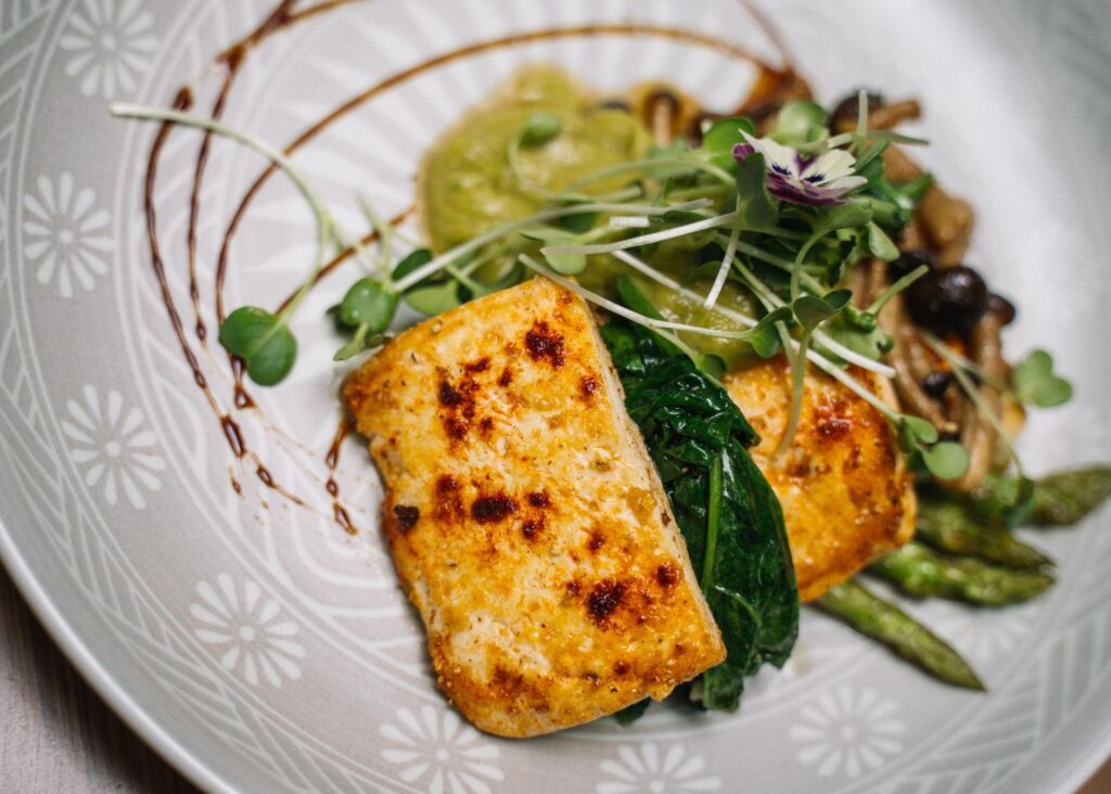 Seared slices with greens, mushrooms and microgreens on a plate