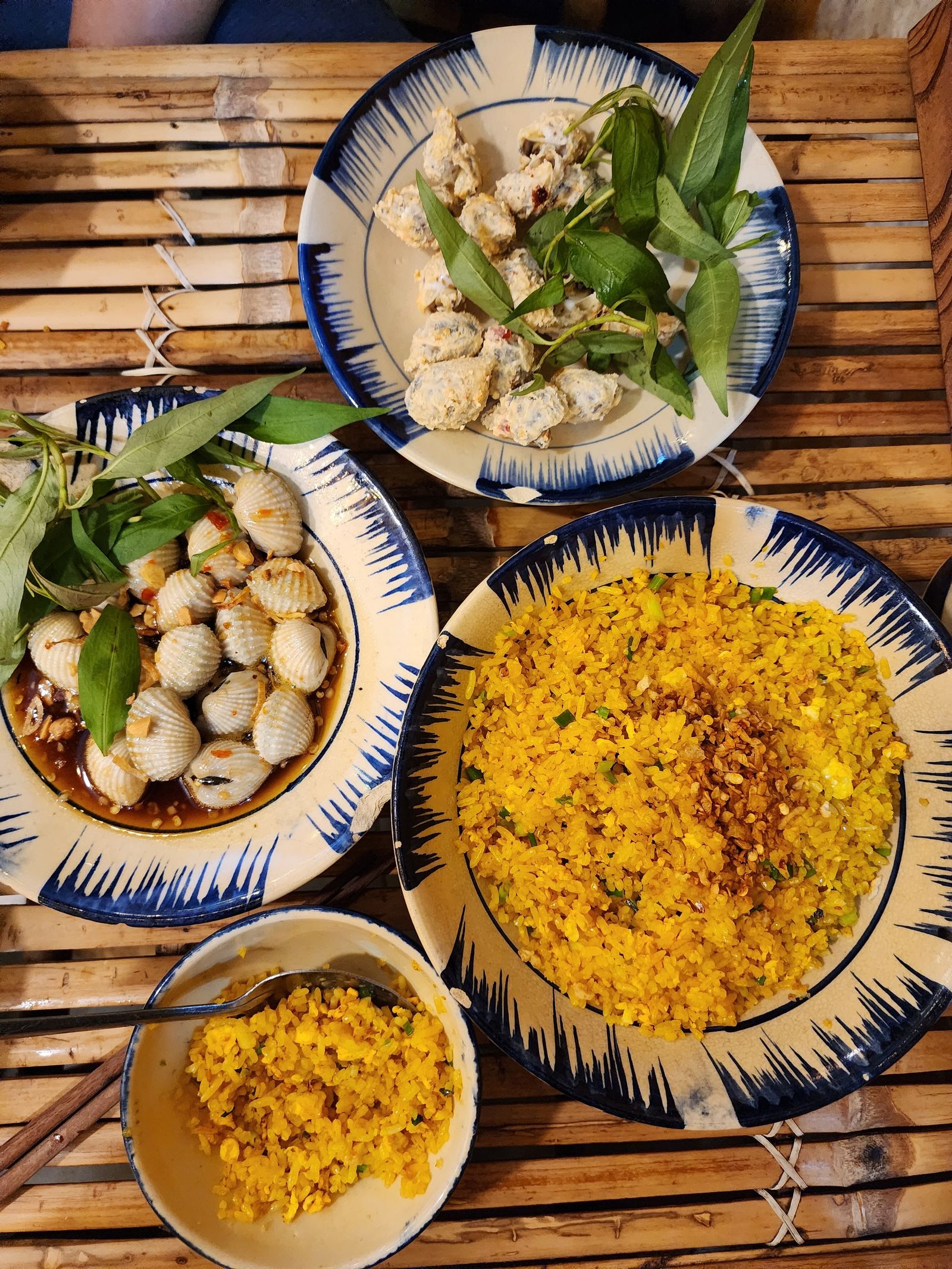 Vietnamese meal of clam dishes with fried clams, clams in sauce and rice on a bamboo table