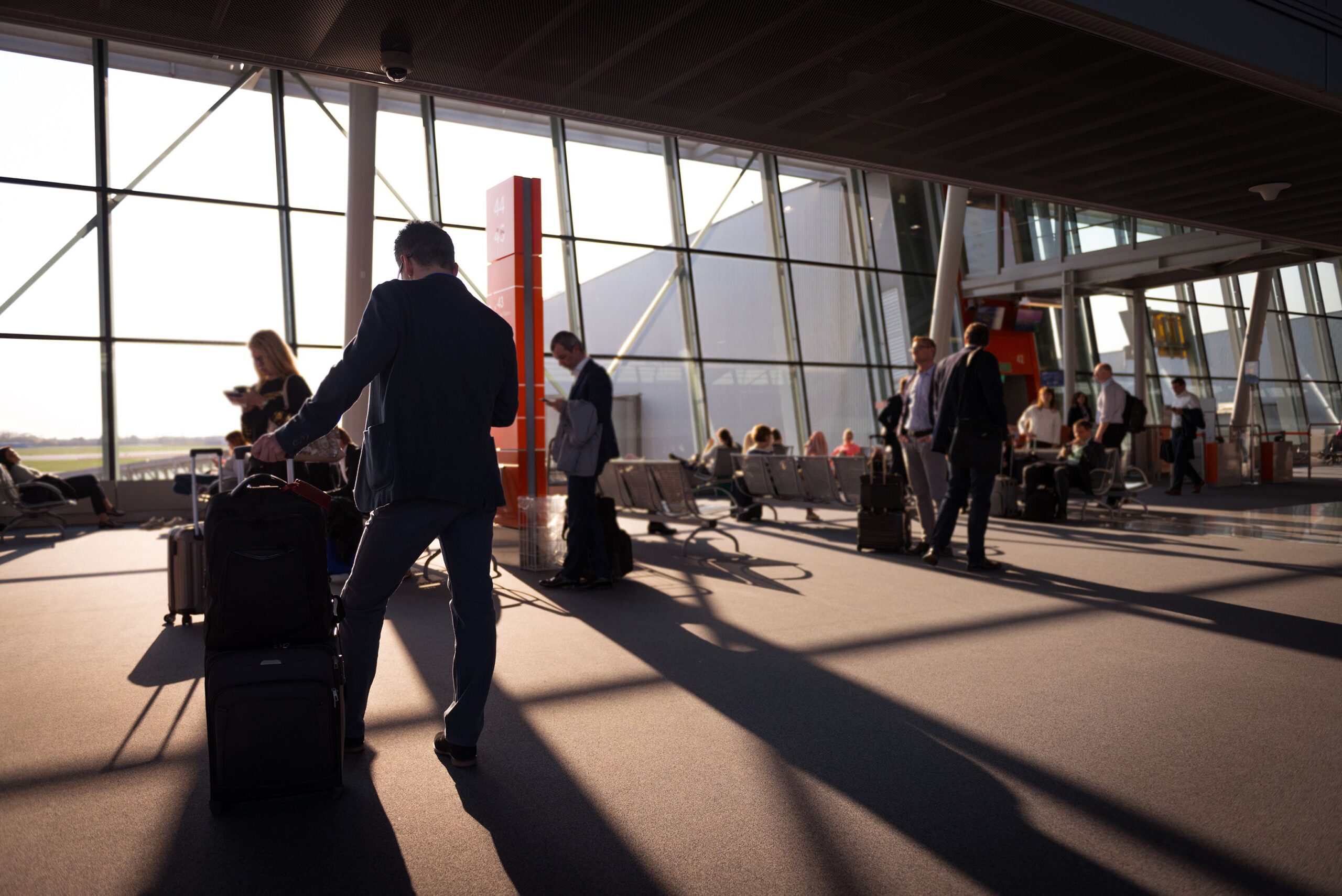 Travelers with luggage waiting inside an airport terminal