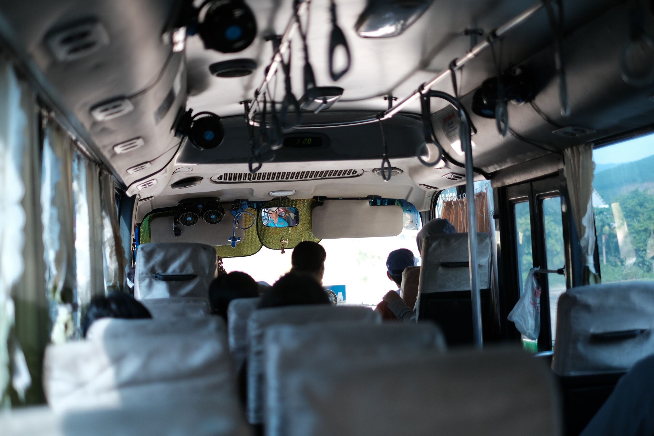 Passengers seated inside a bus with green hills visible through the windows
