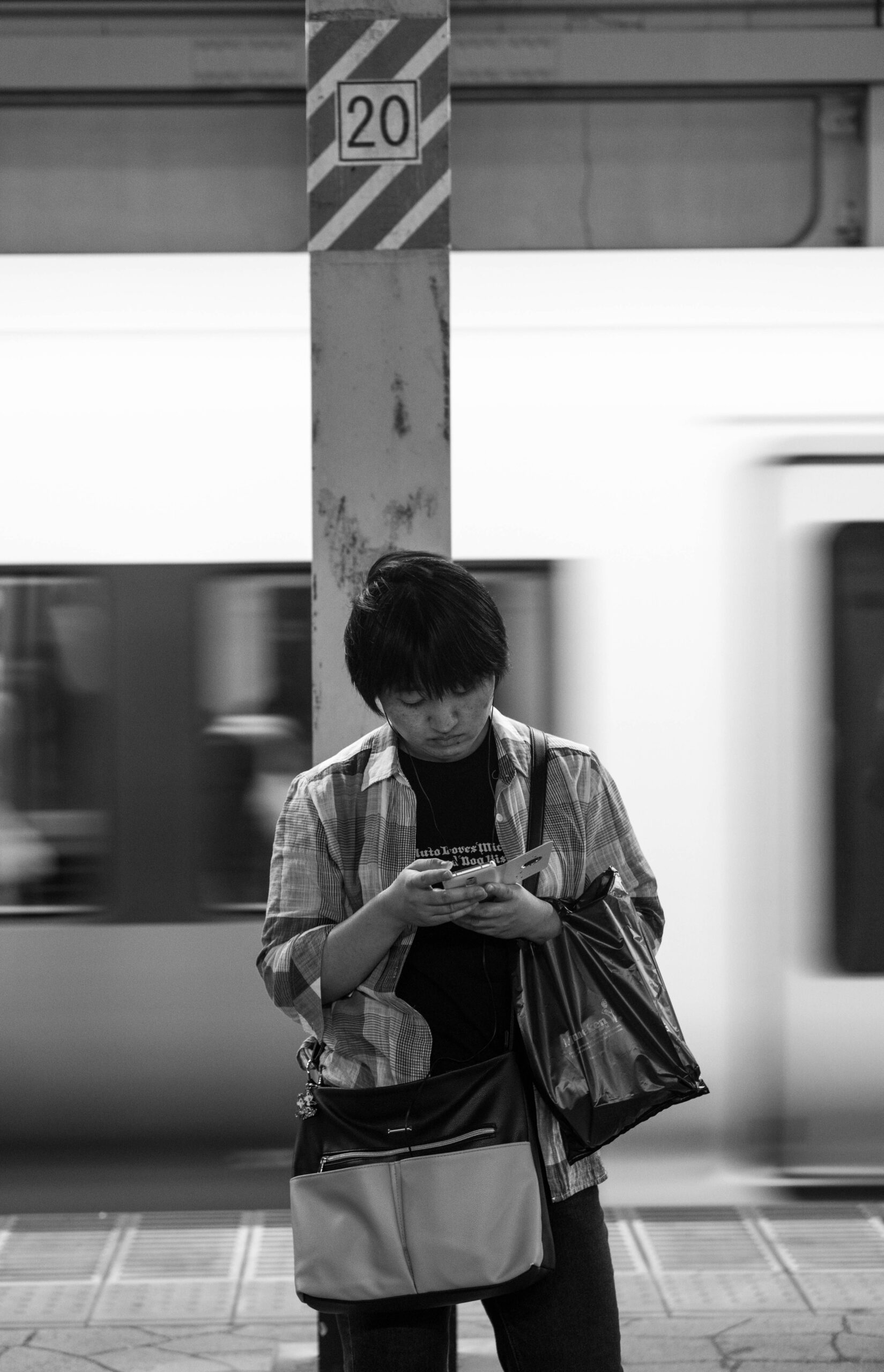 A man checks his phone at a subway station as a train passes