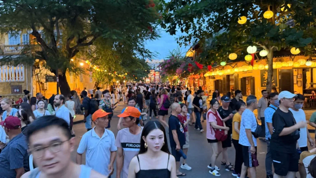 Visitors move through a crowded lantern-lit pedestrian street in Hoi An at dusk.