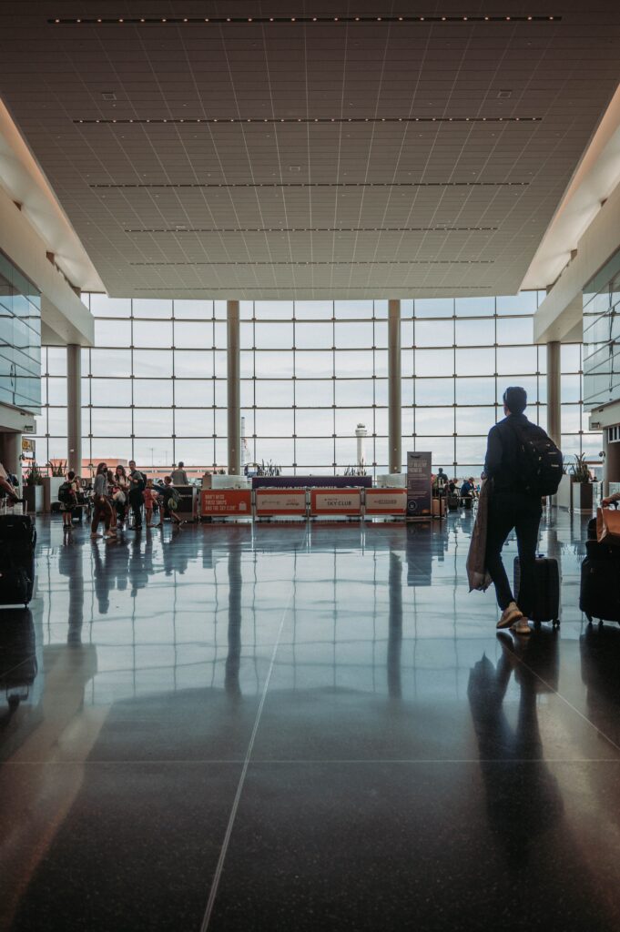 A traveler walks through an airport terminal pulling a suitcase.
