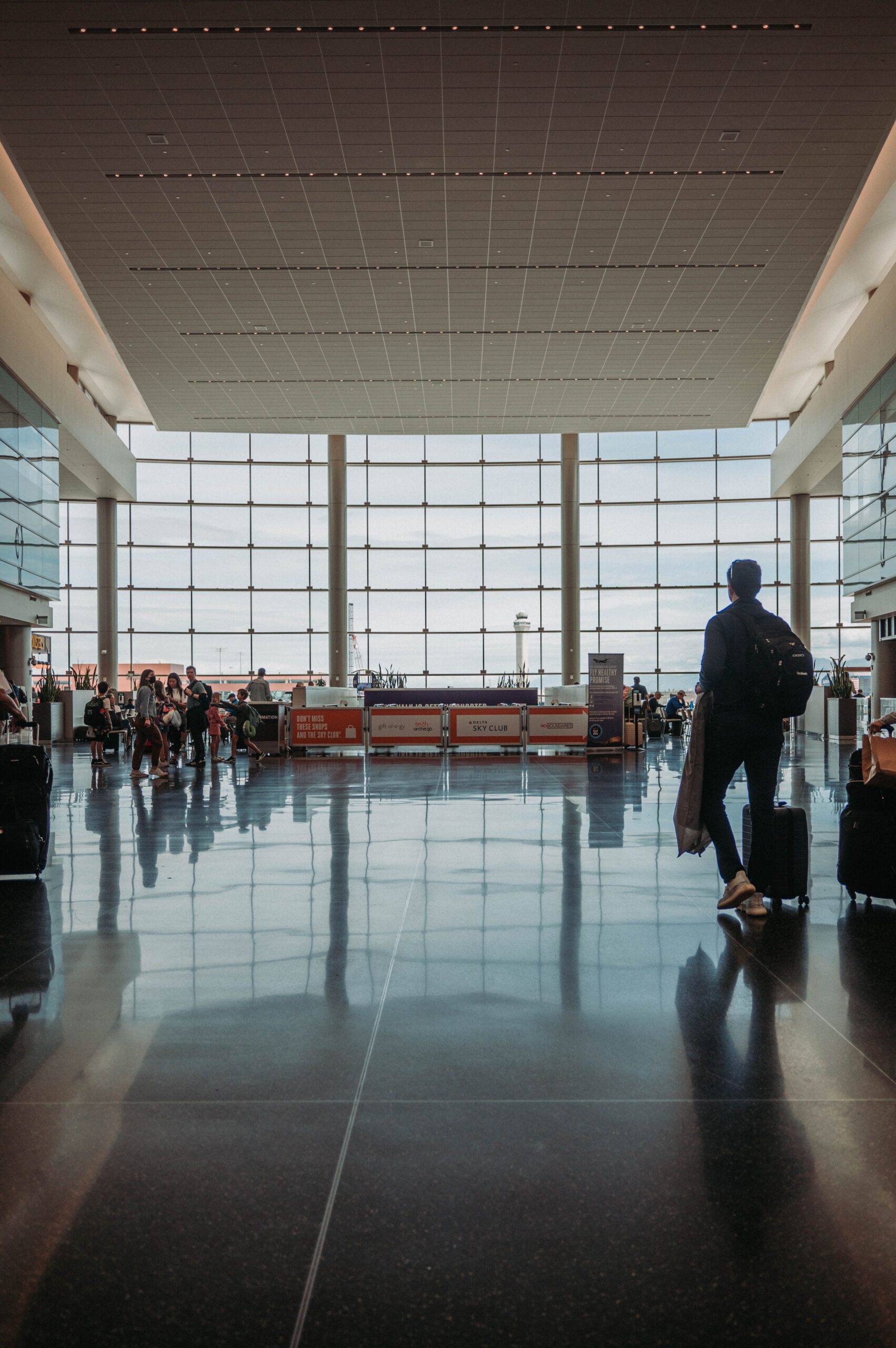 A traveler walks through an airport terminal pulling a suitcase.