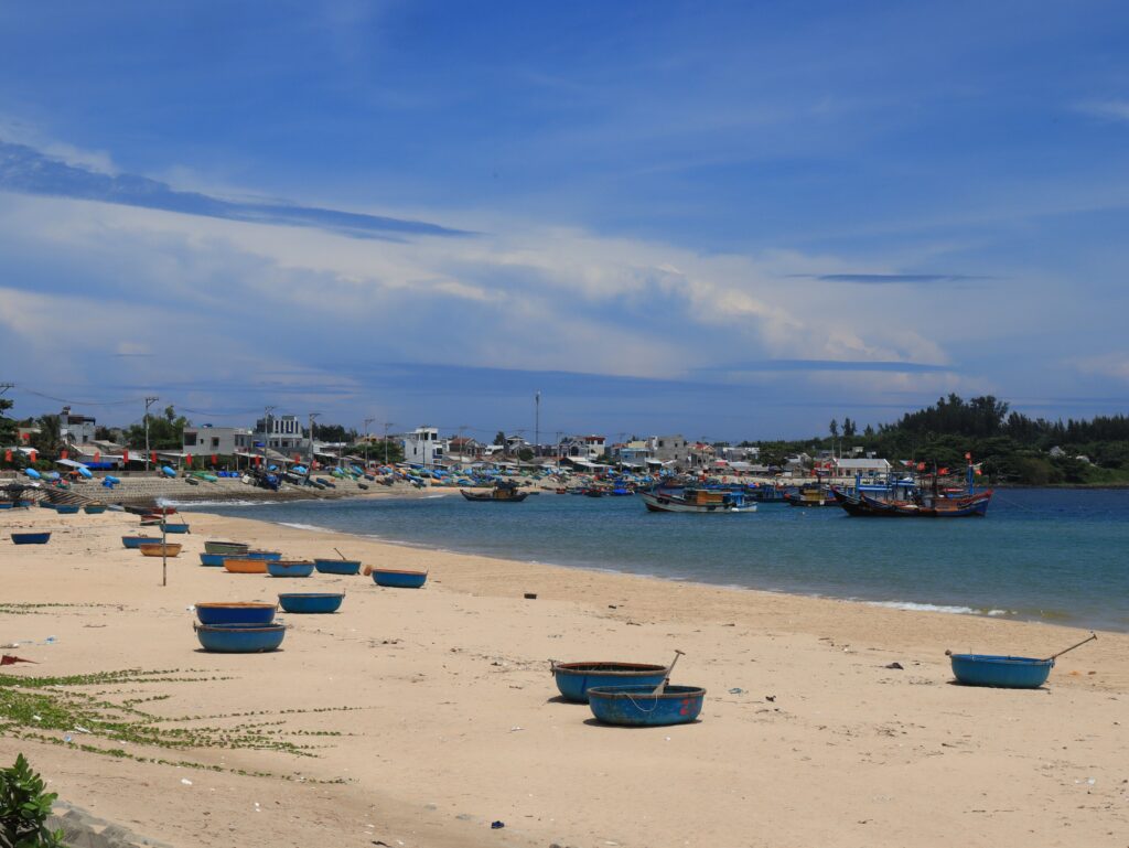 Vietnamese fishing boats on a sandy beach beside a coastal village