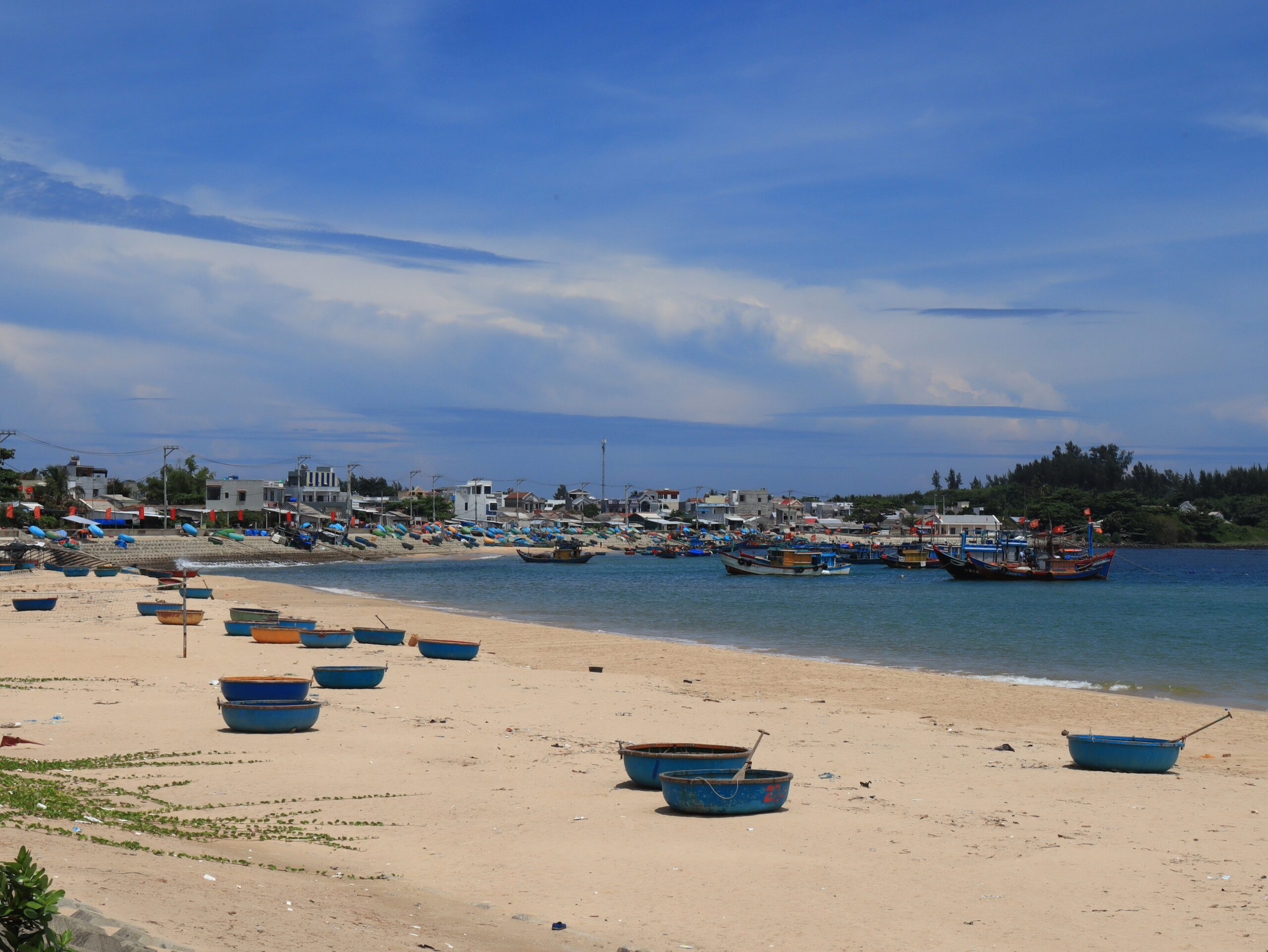 Vietnamese fishing boats on a sandy beach beside a coastal village