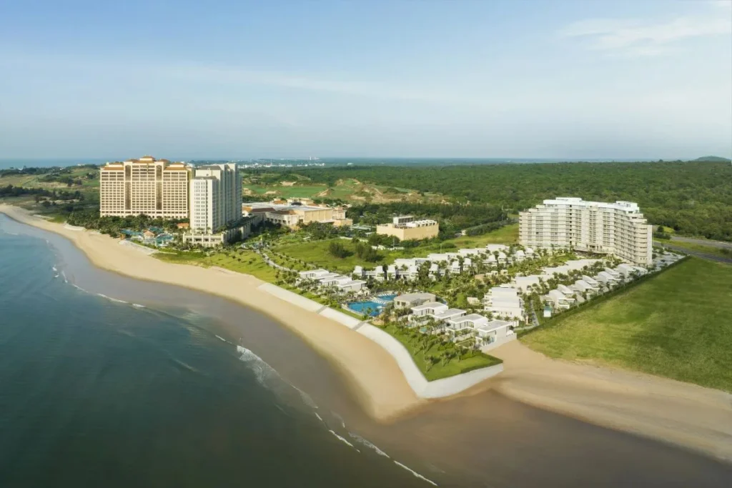Aerial view of a coastal resort complex beside a sandy beach.