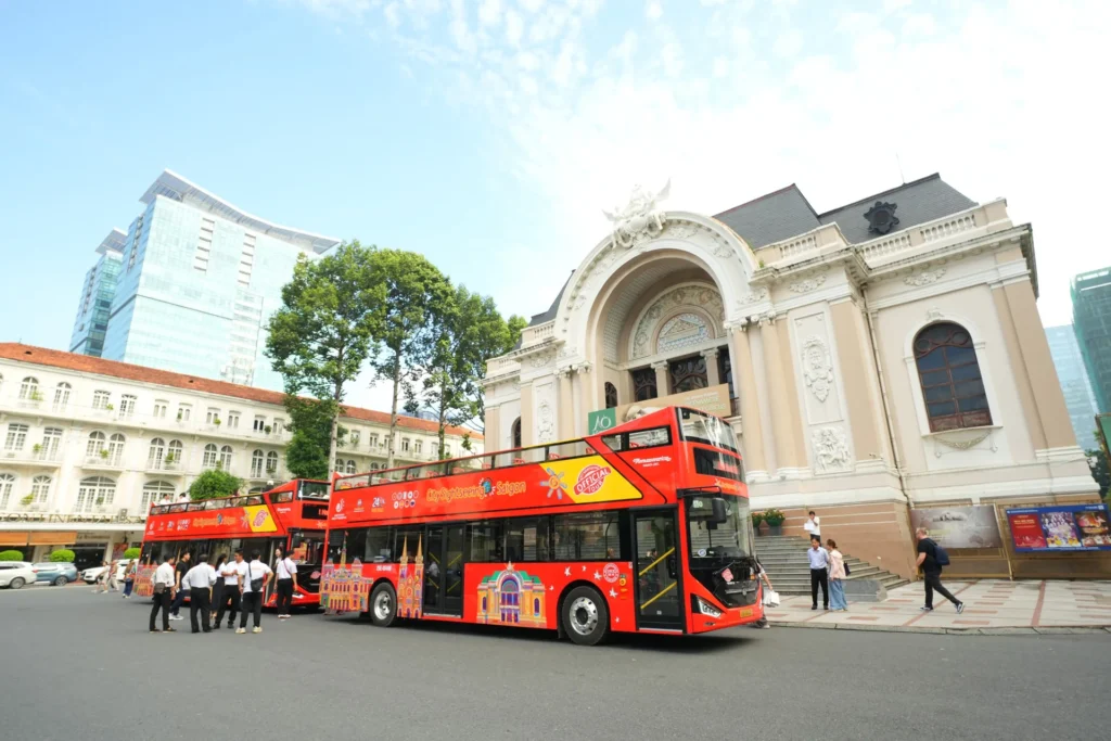 Two red double-decker sightseeing buses on a Ho Chi Minh City street.