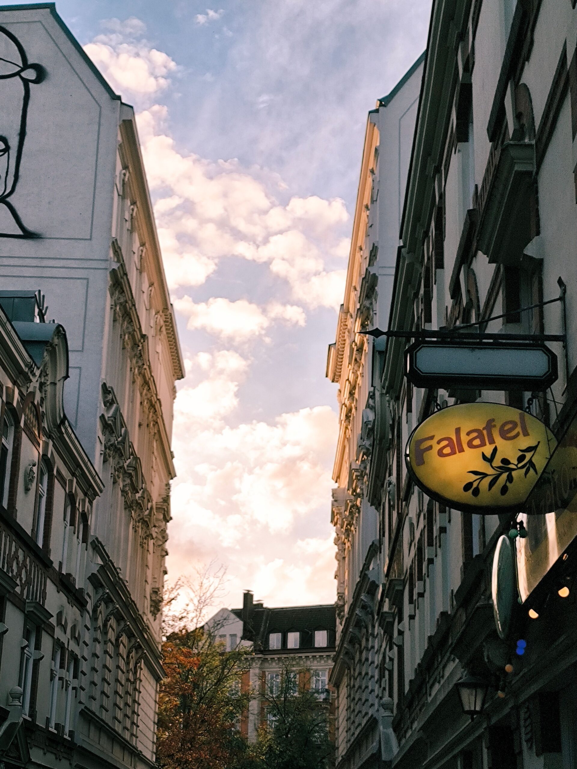 Narrow St. Pauli alley between tall buildings with a falafel sign