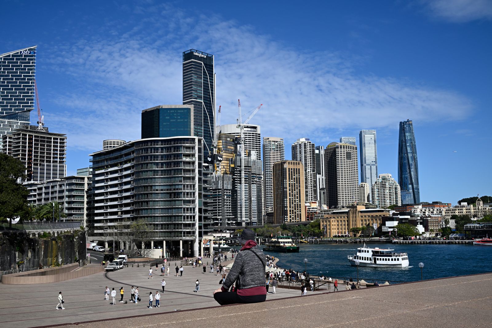 Visitors on a Sydney Harbour promenade with the skyline and a boat
