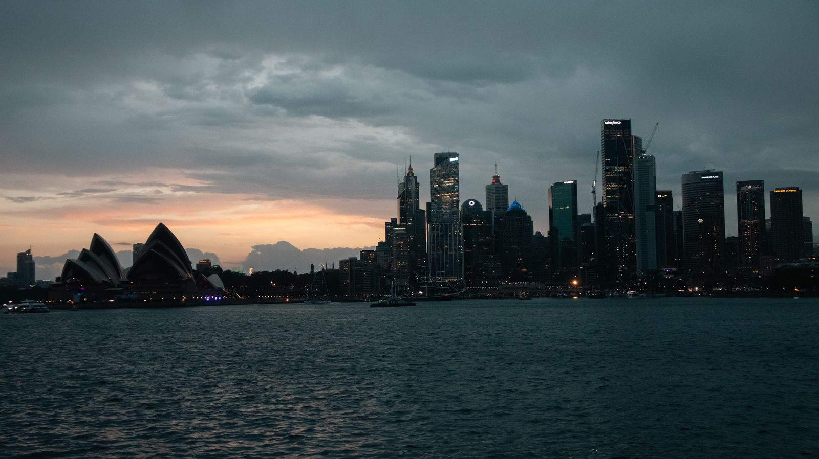 Sydney Opera House and city skyline across the harbour at dusk