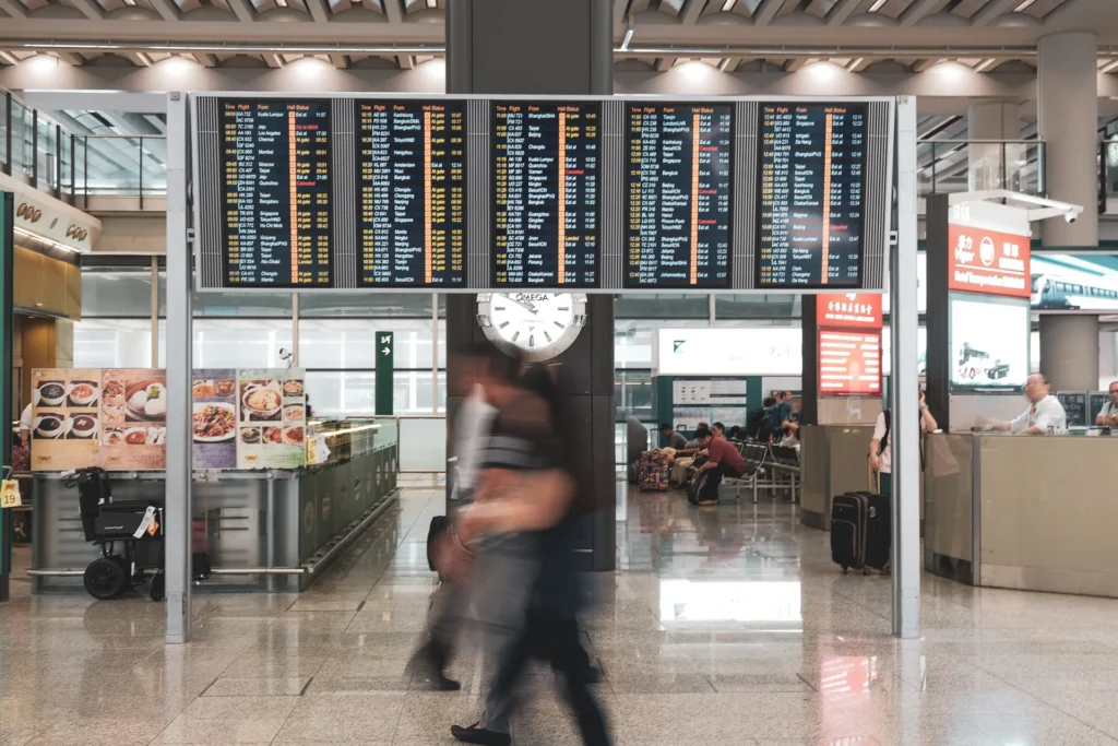 Travelers passing a flight information board in an airport terminal