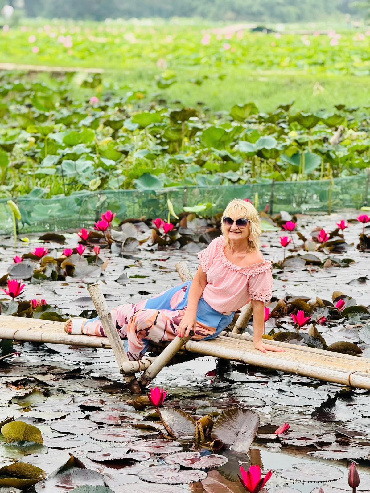 Guest beside a flower-covered pond at Mua Cave
