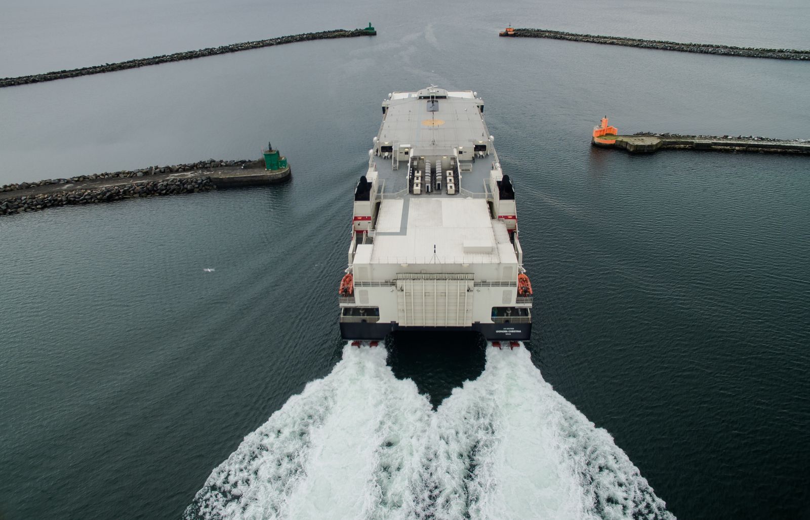 Ferry leaving a harbor between breakwaters