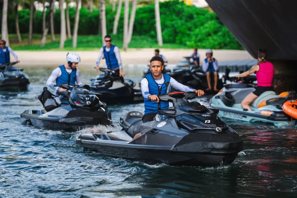 Several jet skis with riders on the water.