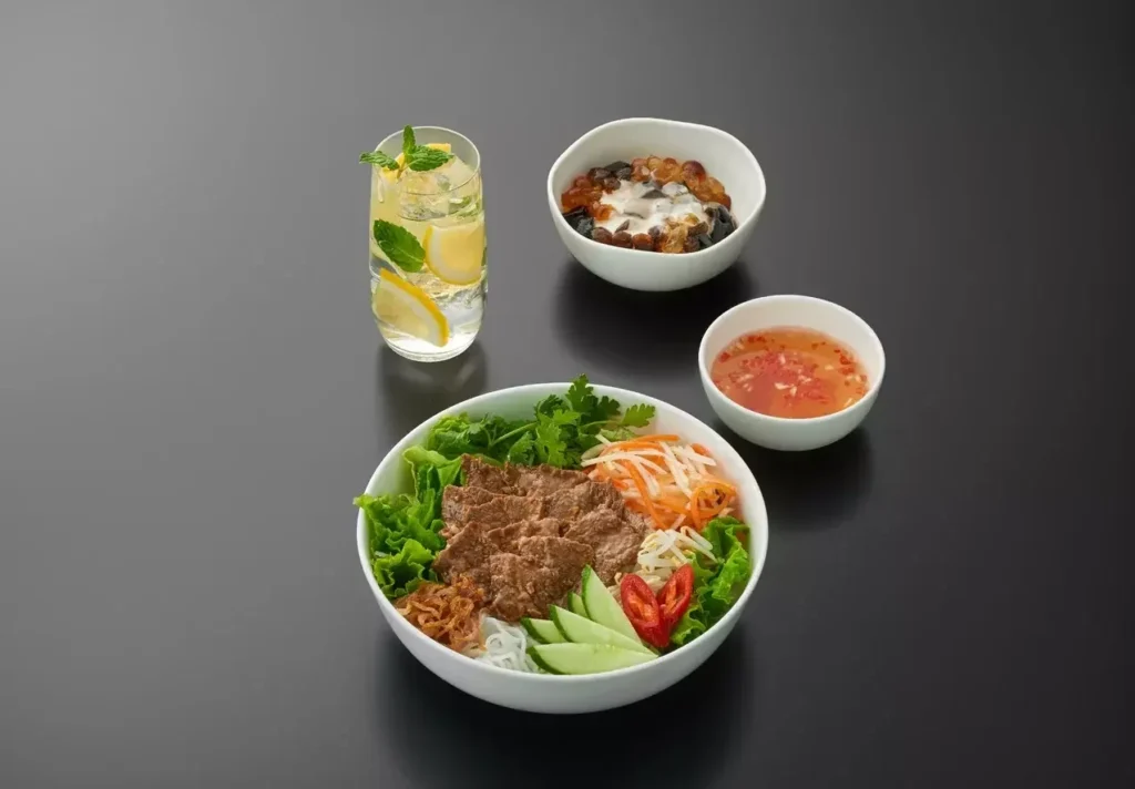 Bun bo Nam Bo with side dishes and a drink.