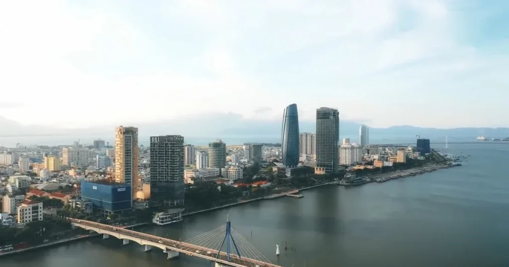 Aerial view of a riverfront city skyline and a cable-stayed bridge.