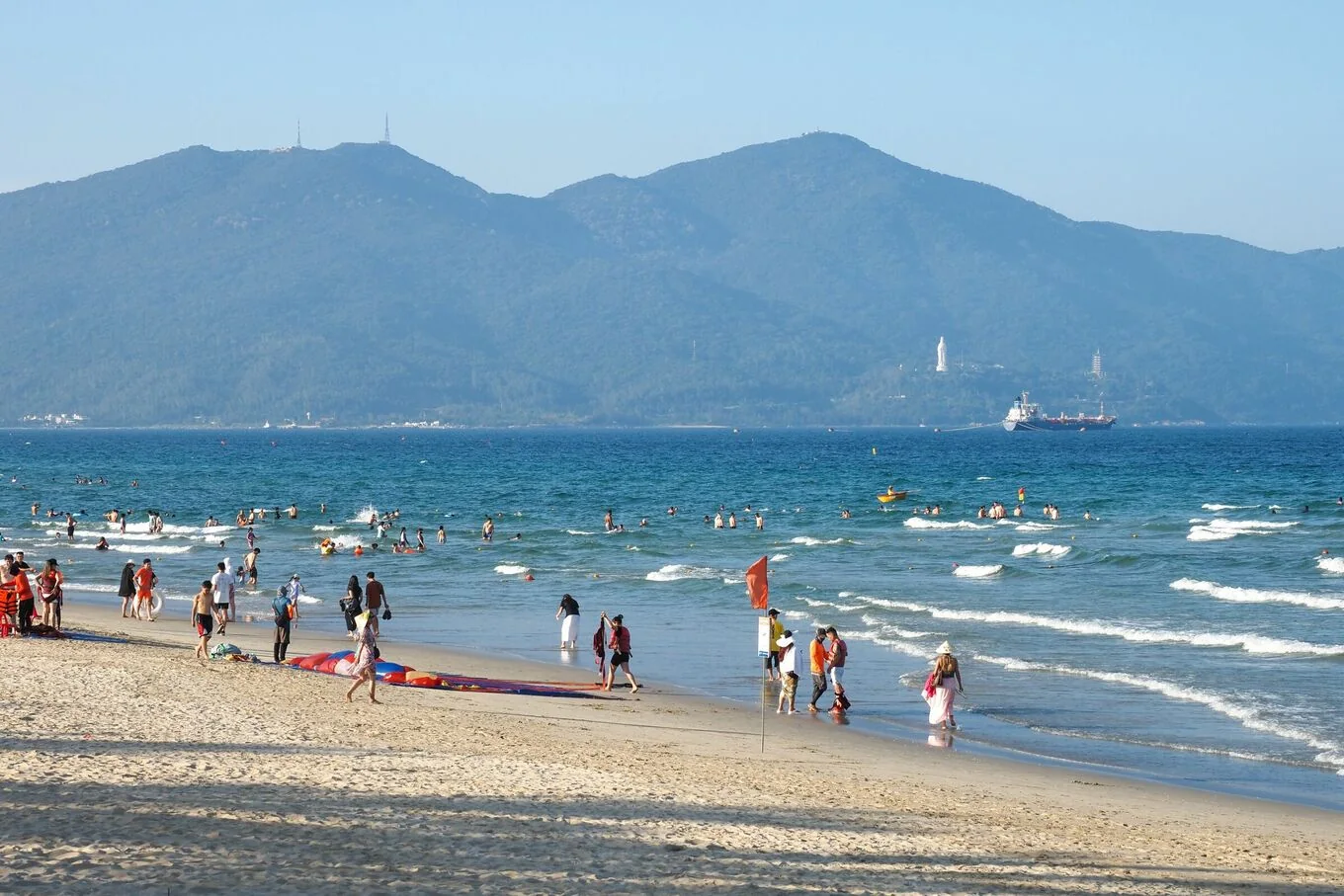Visitors swimming and walking along a sandy beach in Da Nang.