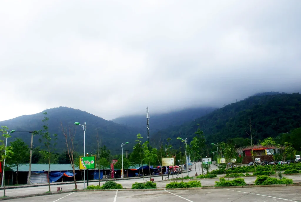 Yen Tu Mountain in Quang Ninh under low cloud, with a roadside area in the foreground.