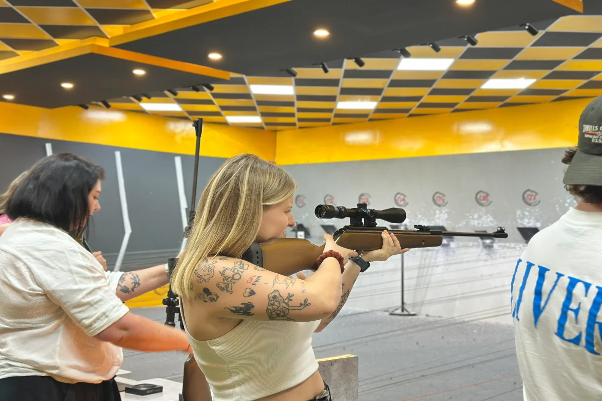 A guest practising sport shooting with staff guidance at the indoor range