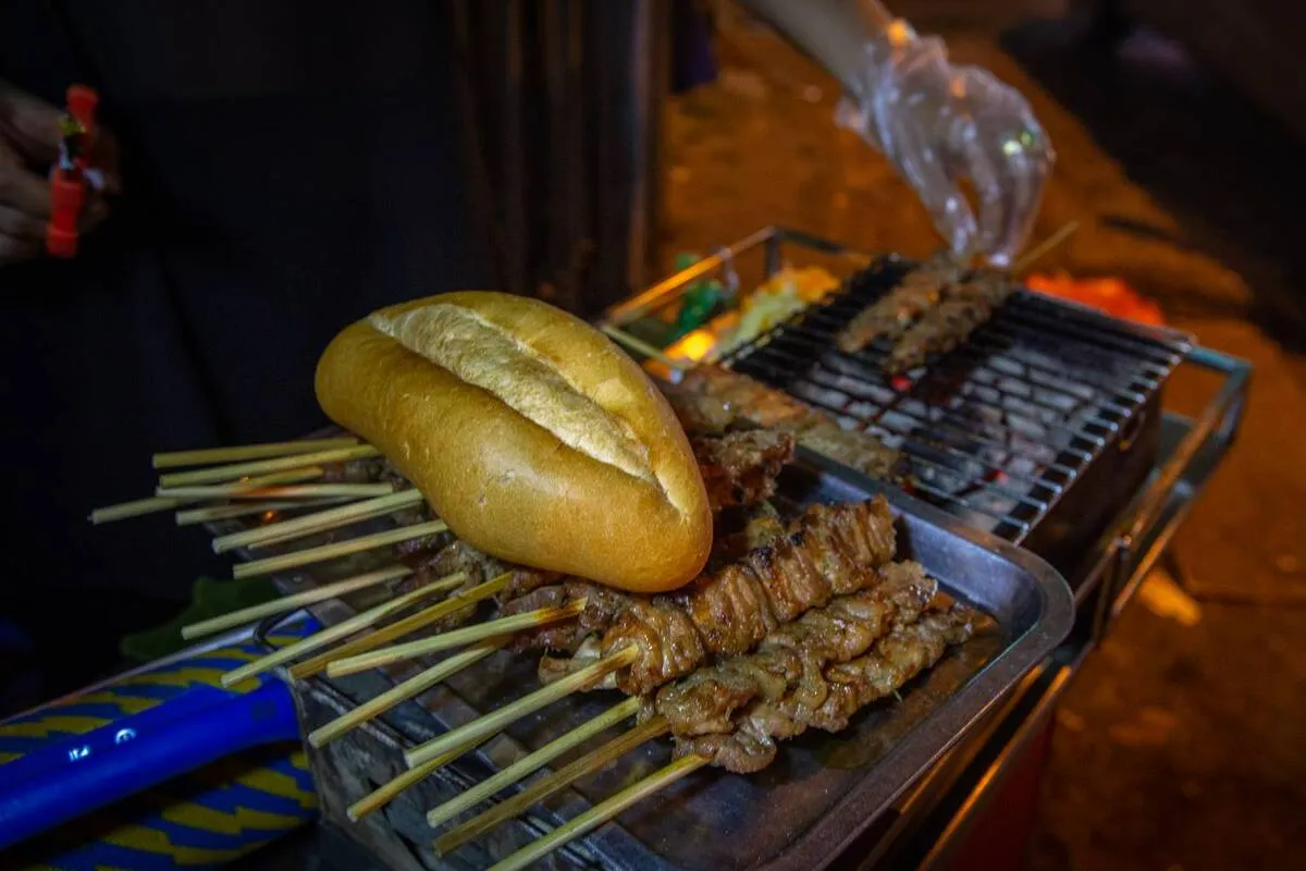Grilled pork skewers and bread at a Hanoi street food stall