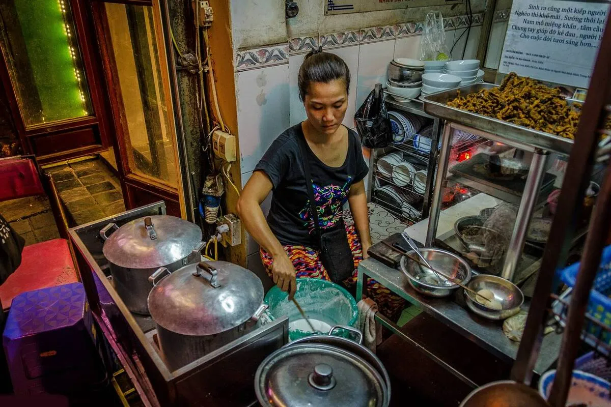A vendor preparing food in a small Hanoi eatery