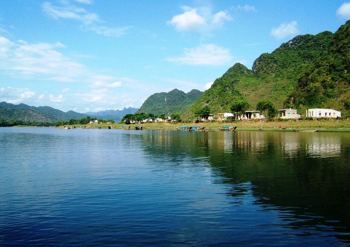 Blue water, riverside boats and forested limestone mountains along the Son River.